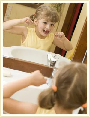 Little girl flossing her teeth in front of a mirrow