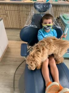 Child patient with a mask and the emotional support dog on him