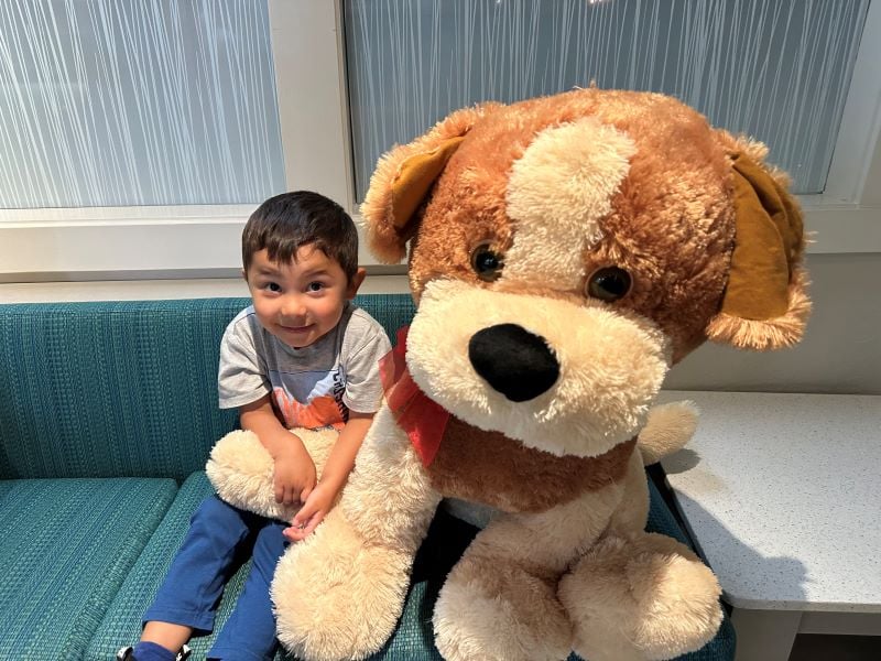 little boy at our office smiling next to giant stuffed puppy
