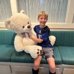 Child's first visit to dentist posing with our large teddy bear