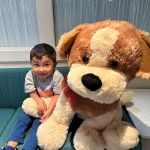 little boy at our office smiling next to giant stuffed puppy