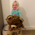 little girl posing with large brown teddy bear