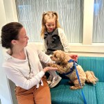 Staff member and child petting dog in clinic waiting area